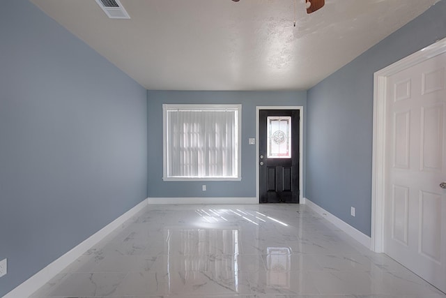 foyer with a ceiling fan, marble finish floor, visible vents, and baseboards