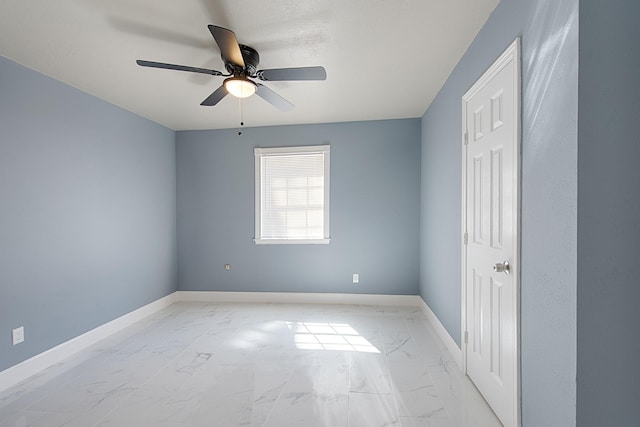 unfurnished room featuring marble finish floor, ceiling fan, and baseboards