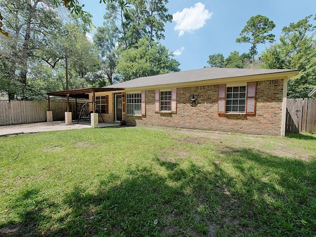 rear view of house featuring a yard, fence private yard, brick siding, and a patio