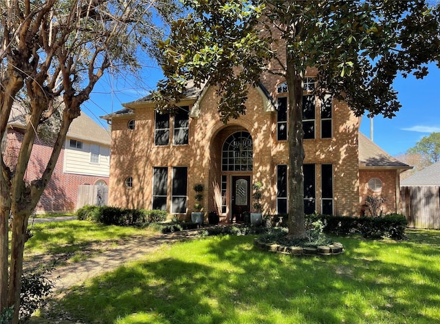 view of front facade with a front yard, brick siding, and fence