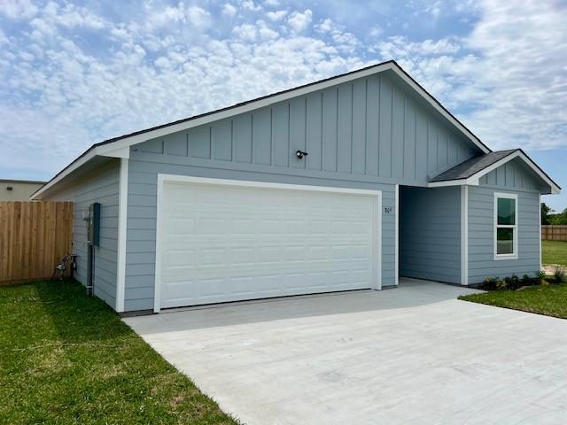 809 Flycatcher Dr, Palacios, TX 77465 - view of front of home with concrete driveway, board and batten siding, fence, and a garage