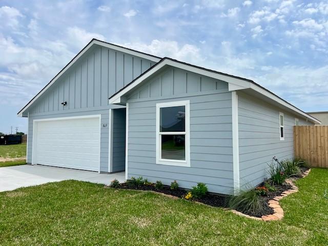 809 Flycatcher Dr, Palacios, TX 77465 - view of front facade with concrete driveway, board and batten siding, fence, and a front lawn
