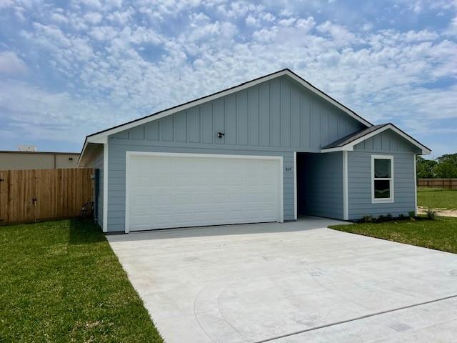 809 Flycatcher Dr, Palacios, TX 77465 - ranch-style house featuring board and batten siding, fence, an attached garage, concrete driveway, and a front yard
