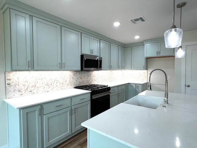 809 Flycatcher Dr, Palacios, TX 77465 - kitchen with a sink, visible vents, stainless steel microwave, black range with gas cooktop, and decorative backsplash