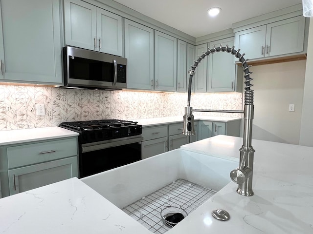 809 Flycatcher Dr, Palacios, TX 77465 - kitchen with light stone countertops, stainless steel microwave, black range with gas cooktop, and backsplash