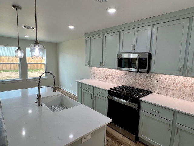 809 Flycatcher Dr, Palacios, TX 77465 - kitchen with black gas range oven, a sink, visible vents, stainless steel microwave, and decorative backsplash