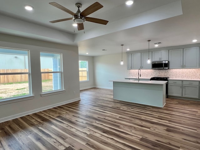 809 Flycatcher Dr, Palacios, TX 77465 - kitchen with gray cabinetry, dark wood-type flooring, stainless steel microwave, and backsplash