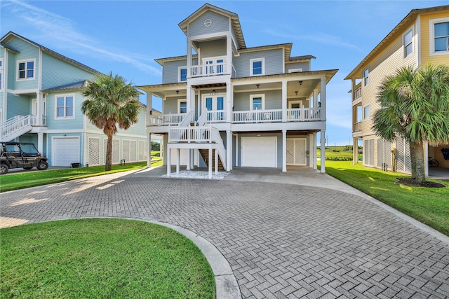 raised beach house with a porch, a front yard, decorative driveway, and a balcony