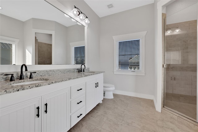 bathroom featuring double vanity, a shower stall, baseboards, and a sink