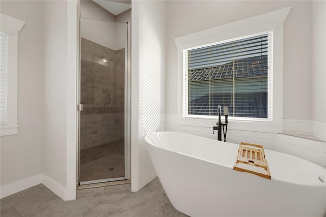 full bathroom featuring a freestanding tub, a shower stall, and baseboards