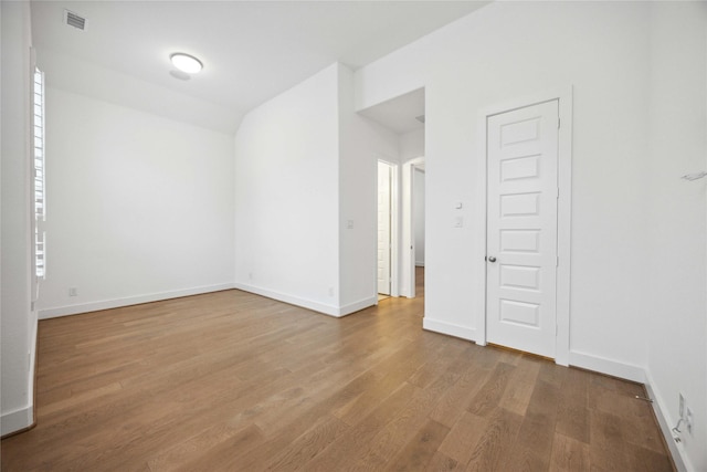 spare room featuring wood finished floors, visible vents, and baseboards