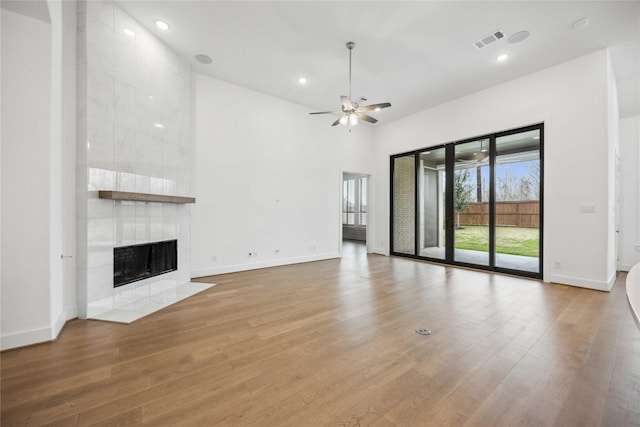 unfurnished living room with light wood-style flooring, visible vents, a fireplace, and ceiling fan