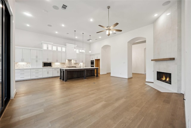 unfurnished living room with a sink, recessed lighting, light wood-style floors, ceiling fan, and a fireplace