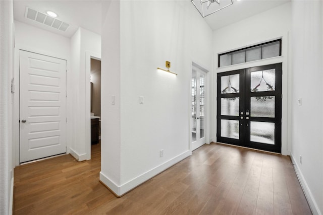 entryway featuring wood finished floors, baseboards, french doors, and visible vents