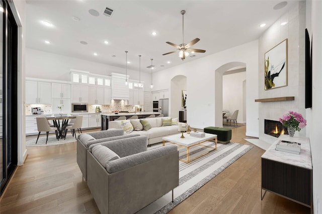 living room with light wood finished floors, arched walkways, recessed lighting, and ceiling fan