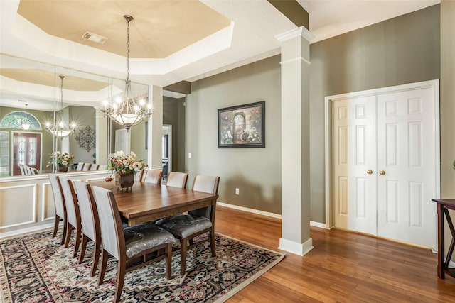 dining space featuring a notable chandelier, a raised ceiling, visible vents, wood finished floors, and baseboards