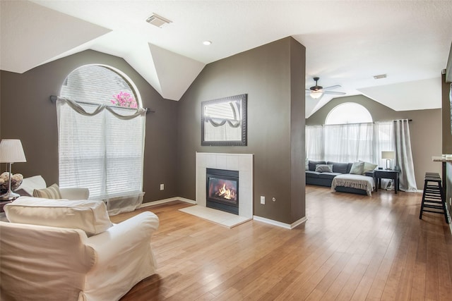 living area featuring light wood-style floors, lofted ceiling, visible vents, and a fireplace