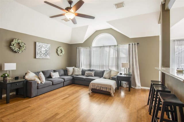 living area with light wood finished floors, ceiling fan, visible vents, and vaulted ceiling