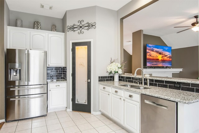 kitchen with tasteful backsplash, appliances with stainless steel finishes, white cabinetry, a sink, and light stone countertops