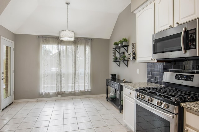 kitchen with vaulted ceiling, white cabinetry, stainless steel appliances, and dark stone counters