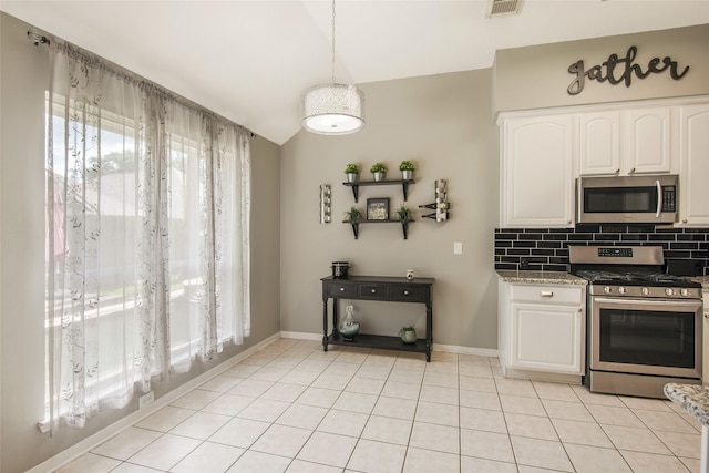 kitchen with stainless steel appliances, decorative backsplash, white cabinetry, vaulted ceiling, and dark stone countertops