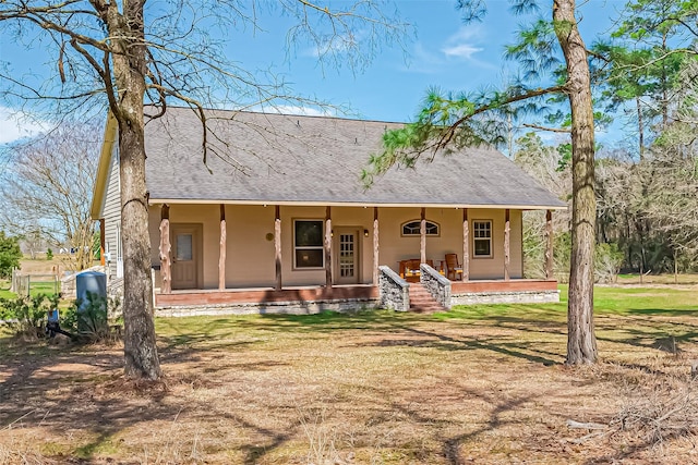 back of property with a yard, a porch, and a shingled roof