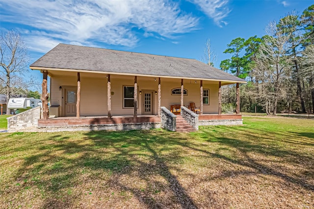 back of property featuring covered porch, roof with shingles, and a yard