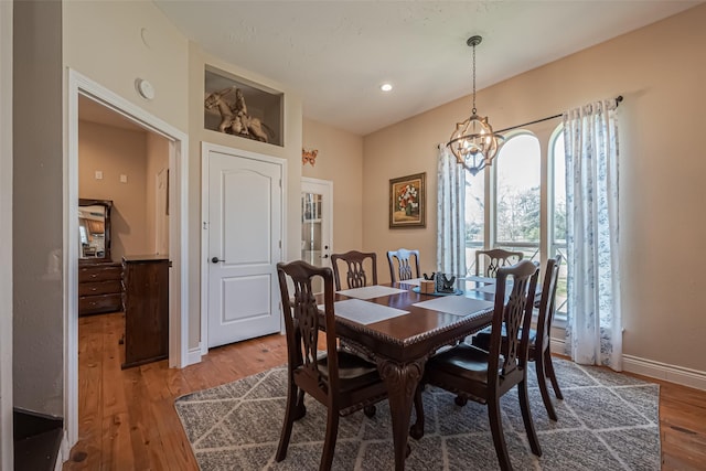 dining room with a notable chandelier, baseboards, wood finished floors, and recessed lighting