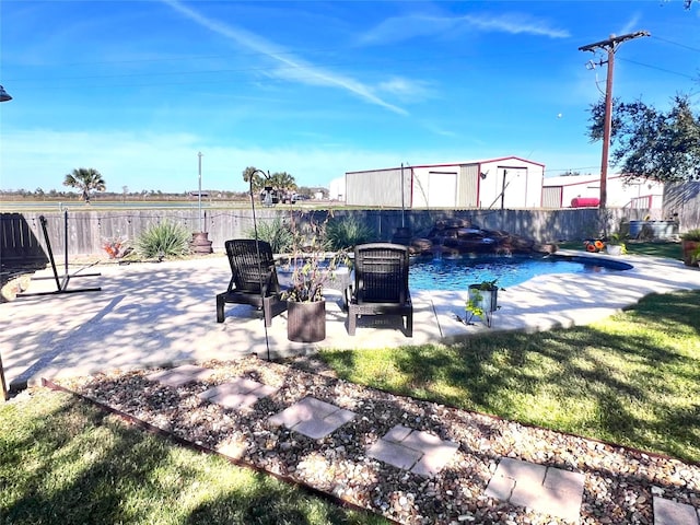 view of swimming pool with a storage unit, a fenced backyard, an outdoor structure, a fenced in pool, and a patio area