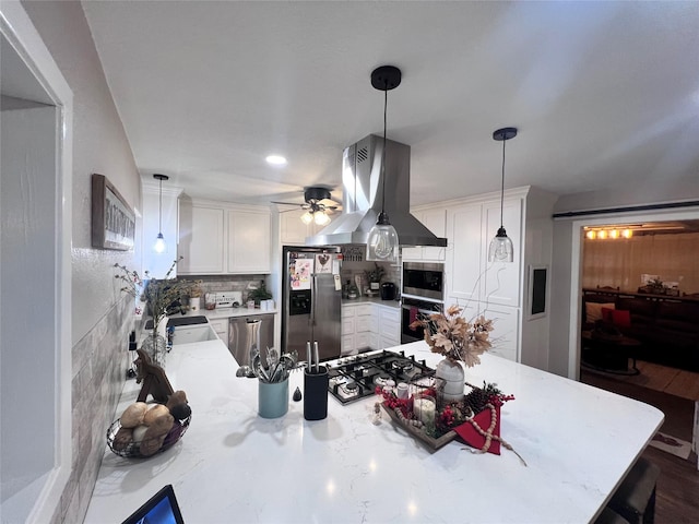 kitchen with tasteful backsplash, appliances with stainless steel finishes, island exhaust hood, a peninsula, and white cabinetry