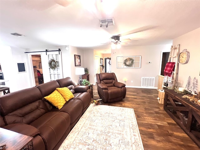 living area with dark wood finished floors, visible vents, and a barn door