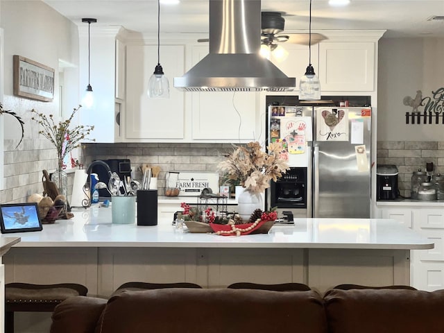 kitchen with light countertops, decorative backsplash, island exhaust hood, stainless steel refrigerator with ice dispenser, and white cabinetry