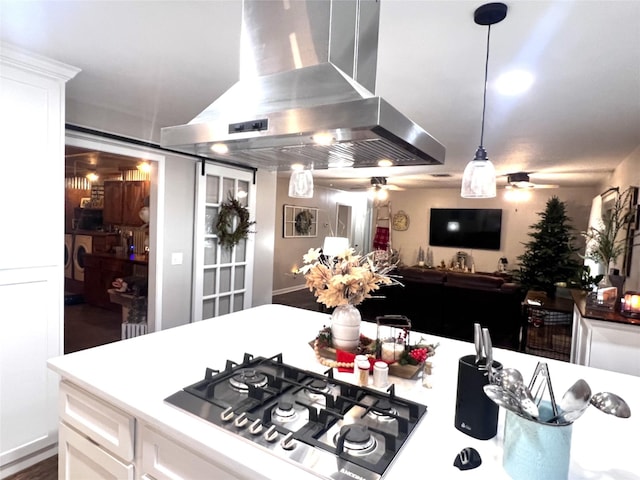 kitchen featuring stainless steel gas cooktop, ceiling fan, white cabinetry, open floor plan, and island range hood