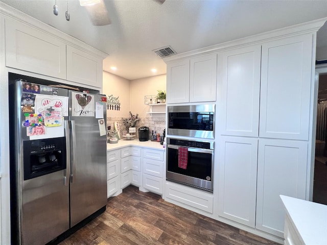 kitchen with dark wood finished floors, light countertops, white cabinetry, and appliances with stainless steel finishes