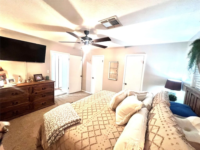 bedroom featuring visible vents, a textured ceiling, a ceiling fan, and carpet floors