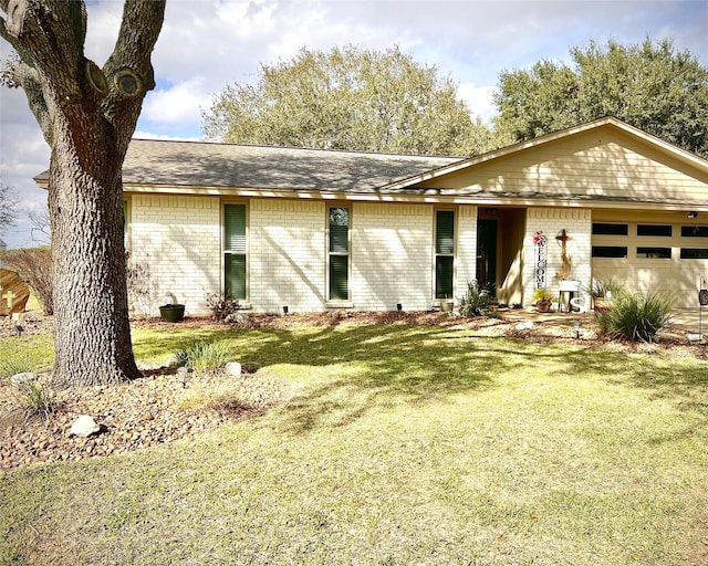 view of front of property featuring brick siding, an attached garage, and a front lawn