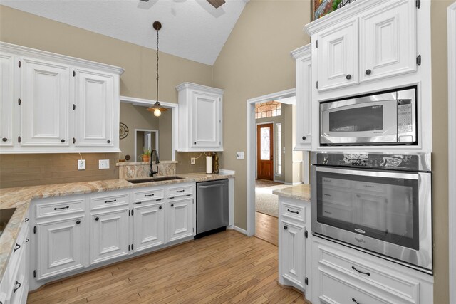 590 Edgewood Dr, Montgomery, TX 77356 - kitchen with stainless steel appliances, vaulted ceiling, white cabinets, tasteful backsplash, and ceiling fan