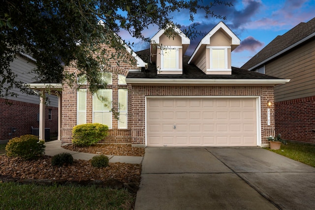 traditional-style home featuring a garage, concrete driveway, and brick siding