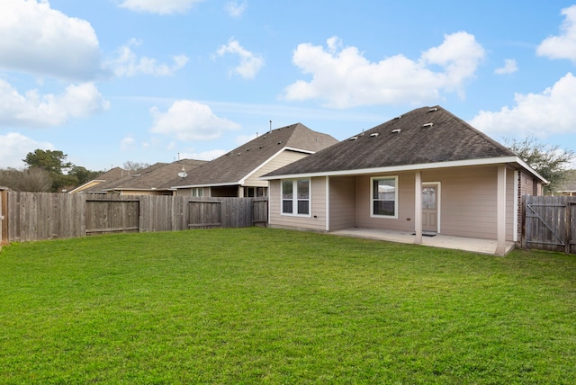 back of property with roof with shingles, a yard, a gate, a patio area, and a fenced backyard