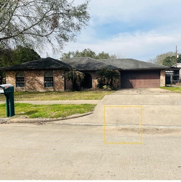 ranch-style house with a shingled roof, concrete driveway, and brick siding