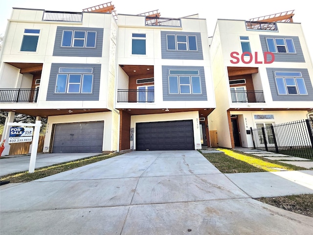 townhome / multi-family property featuring stucco siding, concrete driveway, an attached garage, and fence