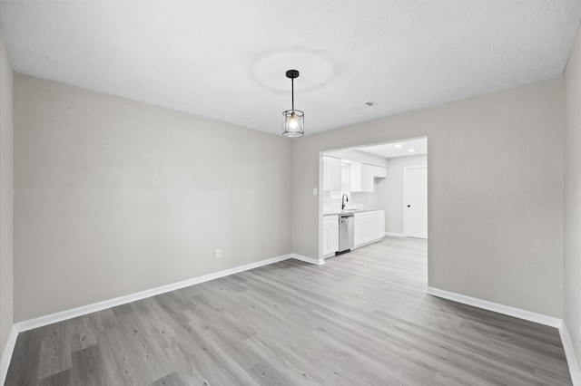 interior space with light wood-style flooring, visible vents, baseboards, and a sink