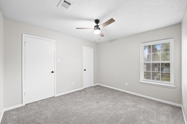 spare room with carpet, visible vents, and baseboards