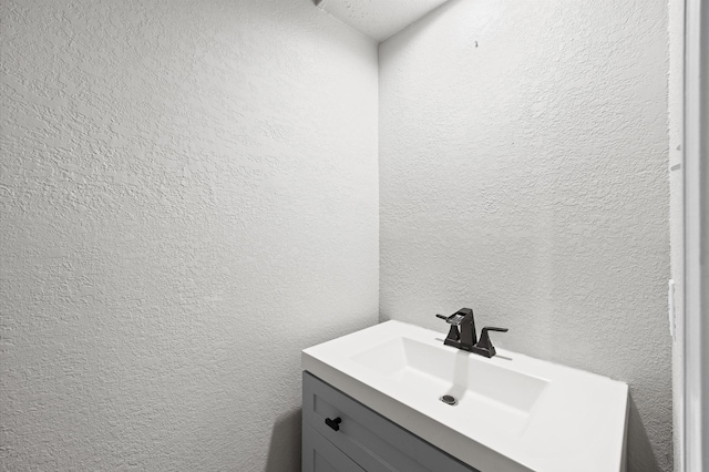 bathroom with a textured wall and vanity