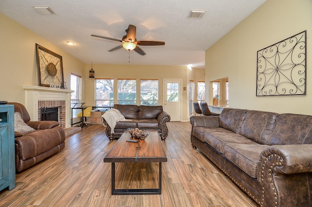 living room with a fireplace, visible vents, and wood finished floors