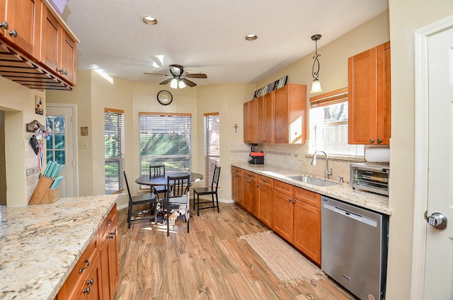 kitchen with light stone counters, a sink, stainless steel dishwasher, tasteful backsplash, and pendant lighting