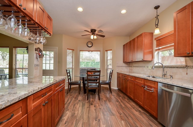 kitchen featuring dishwasher, light stone counters, a sink, and decorative light fixtures