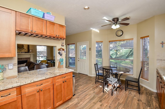 kitchen with a peninsula, light wood finished floors, light stone counters, and a textured ceiling