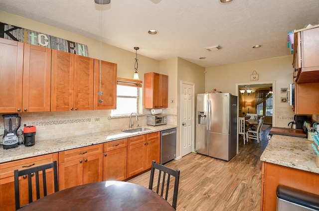 kitchen with stainless steel appliances, a sink, visible vents, backsplash, and pendant lighting