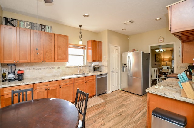 kitchen featuring light wood-style flooring, stainless steel appliances, a sink, visible vents, and hanging light fixtures